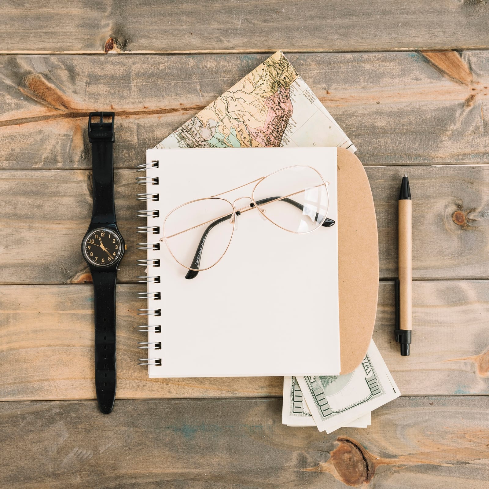 Mesa de trabalho com um relógio de pulso, caderno e acessórios usados na avaliação de uma peça